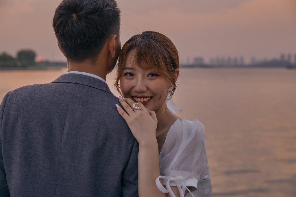 海边夕照下,新娘回眸轻笑、依偎在新郎肩头
